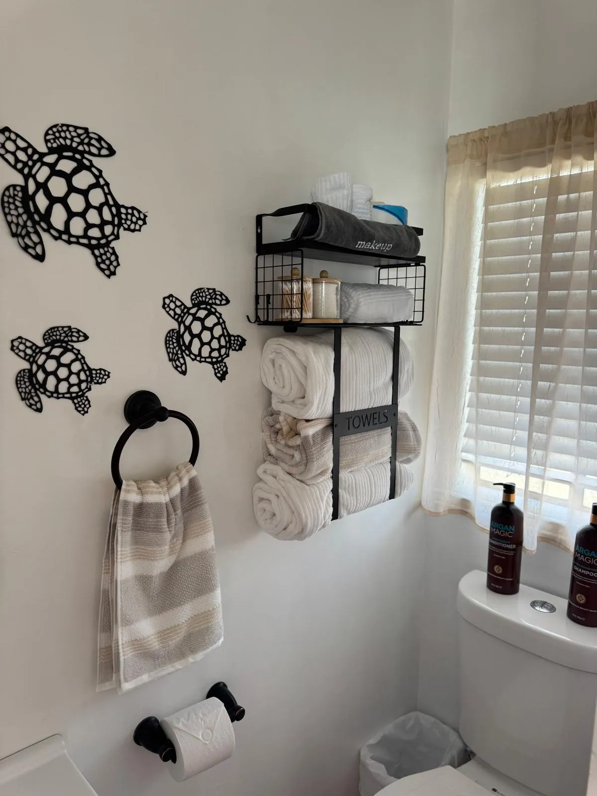 Bathroom with sea-turtle wall art and rolled white towels