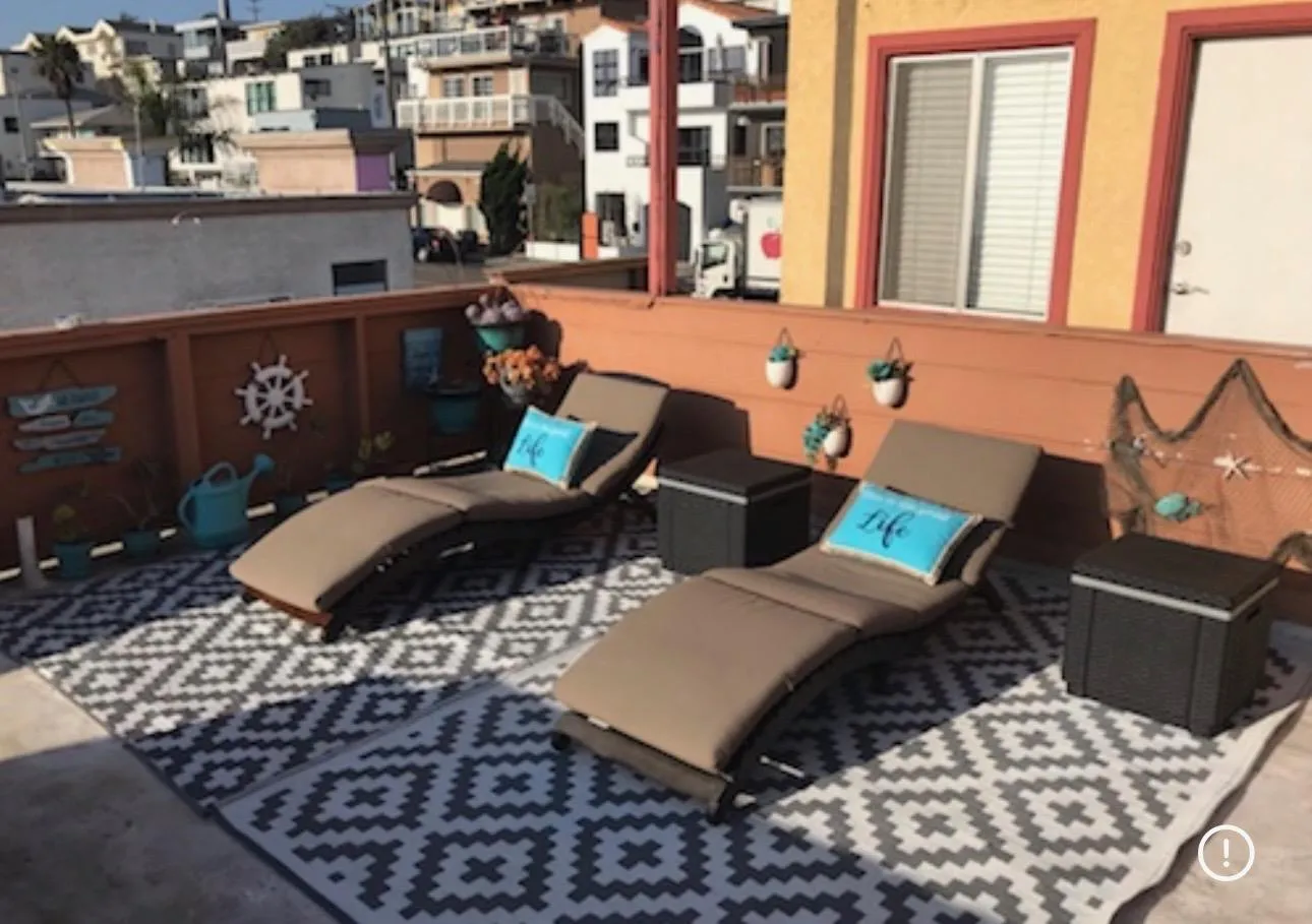Roof deck chaise lounges with terracotta wall and beachy decor